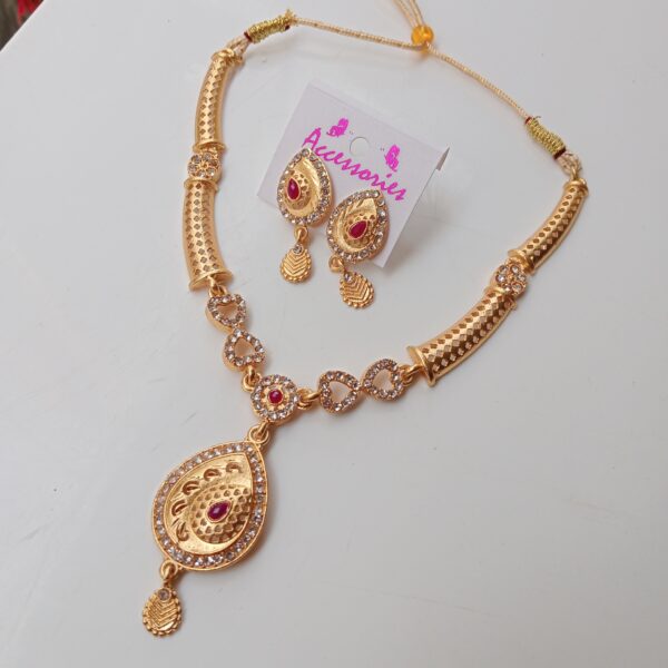 Close-up of gold plated American diamond necklace set highlighting ruby stone centerpiece and crystal detailing.