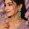 Statement ethnic earrings designed with an elongated silhouette and traditional jhumka bottom. Designer long earrings with white stone-style jhumka detailing